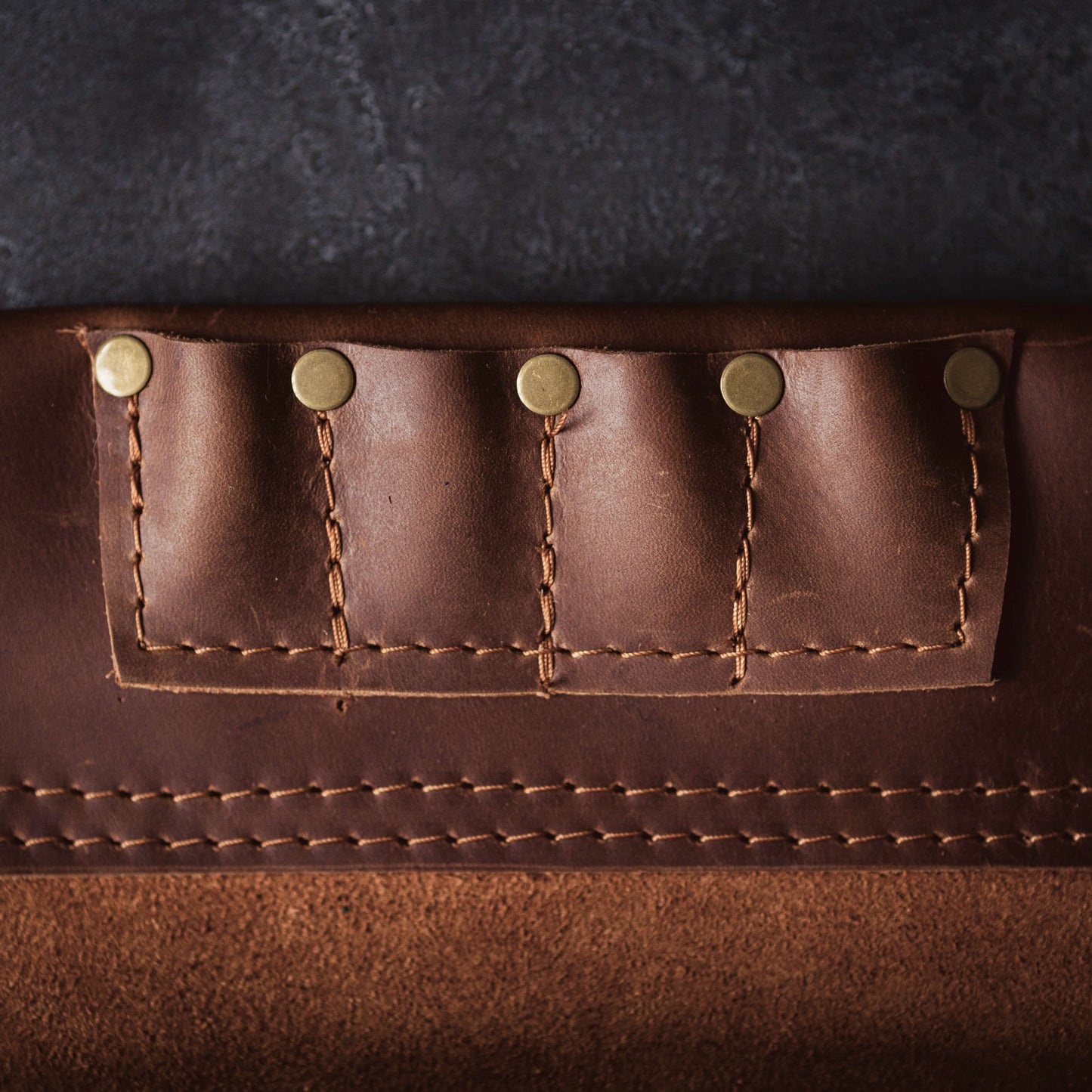 Close-up of a brown leather Belt Bag 1 by The Durham Leatherworker with detailed stitching and metal rivets. The texture highlights the craftsmanship and quality of the material.